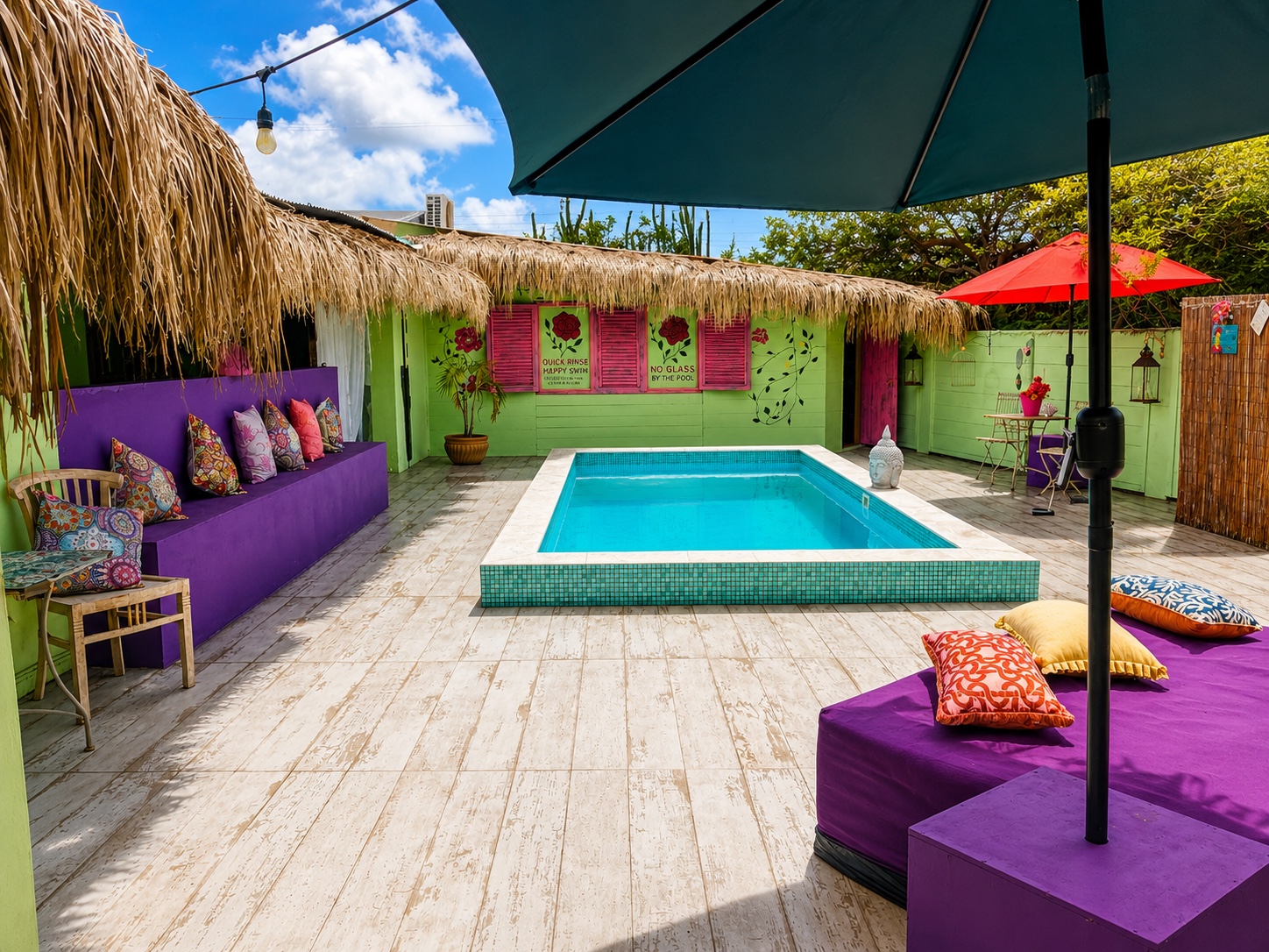 Mammaloe’s Aruba courtyard pool with turquoise water, purple lounge daybed and palapa roof